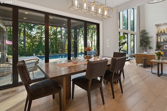 dining area with an inviting chandelier, a healthy amount of sunlight, and light hardwood / wood-style flooring