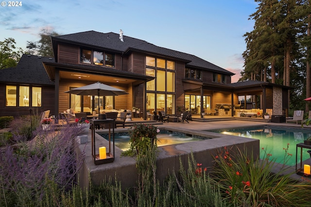 back house at dusk with an outdoor hangout area, a patio area, and a swimming pool with hot tub