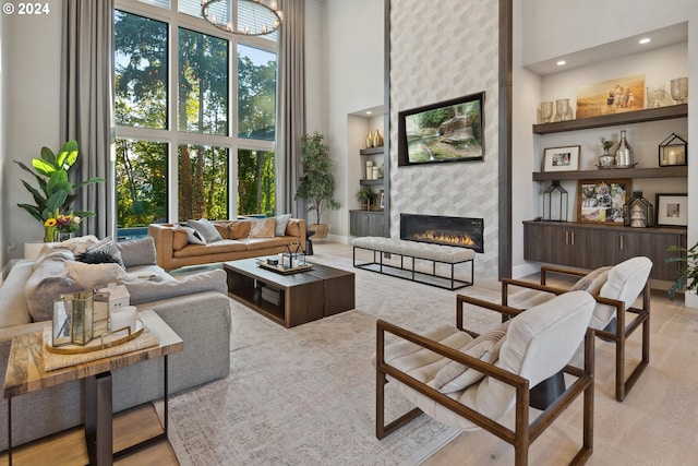 living room with light wood-type flooring, a large fireplace, and a high ceiling