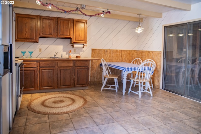 kitchen featuring decorative light fixtures, light tile flooring, sink, and beamed ceiling