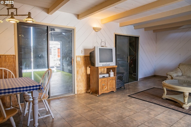 living room with wood walls, beam ceiling, and tile floors