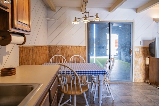 dining space featuring wood walls and beam ceiling