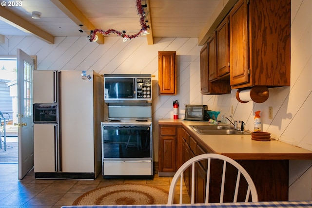 kitchen with white appliances, sink, beamed ceiling, and light tile flooring