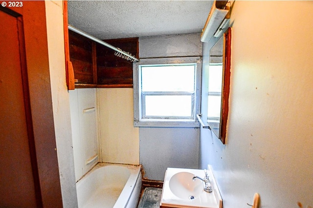 bathroom featuring sink, shower / washtub combination, and a textured ceiling