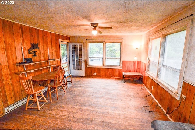 living area with wood walls, ceiling fan, and hardwood / wood-style flooring