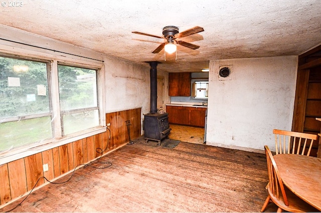 unfurnished room featuring dark hardwood / wood-style floors, ceiling fan, and a wood stove