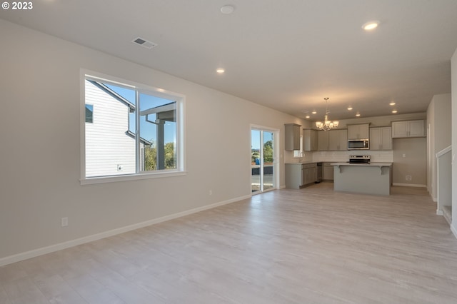 unfurnished living room featuring a notable chandelier and light wood-type flooring