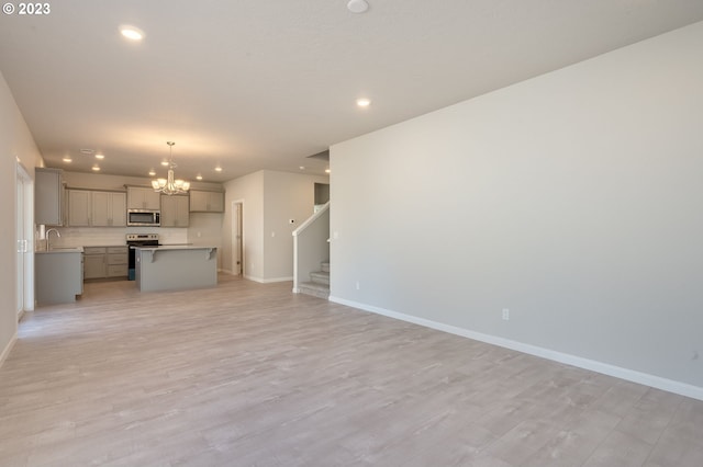 unfurnished living room featuring light hardwood / wood-style floors, sink, and a chandelier