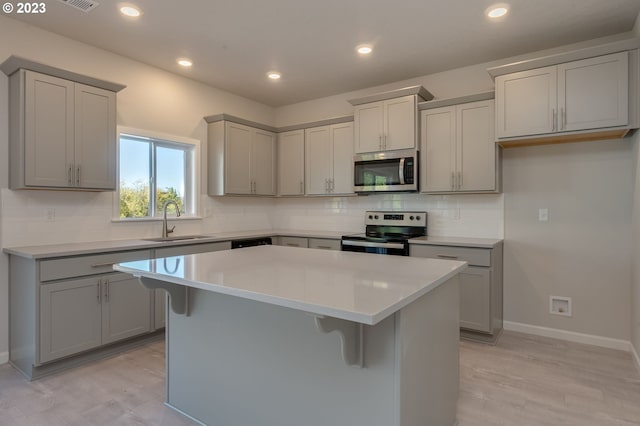 kitchen featuring a kitchen island, stainless steel appliances, sink, and a breakfast bar