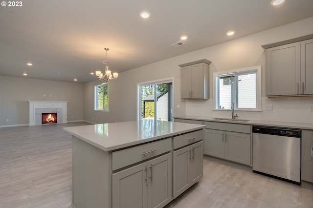 kitchen featuring backsplash, gray cabinetry, stainless steel dishwasher, and a chandelier