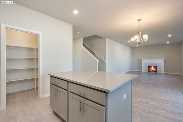 kitchen with a notable chandelier, a center island, gray cabinetry, and light hardwood / wood-style floors