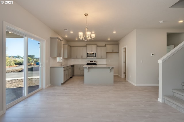 kitchen with hanging light fixtures, stainless steel appliances, gray cabinetry, and a notable chandelier