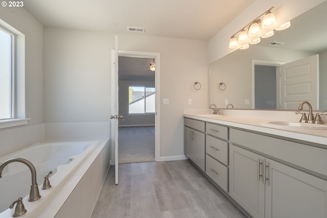 bathroom featuring wood-type flooring, double sink, oversized vanity, and tiled tub