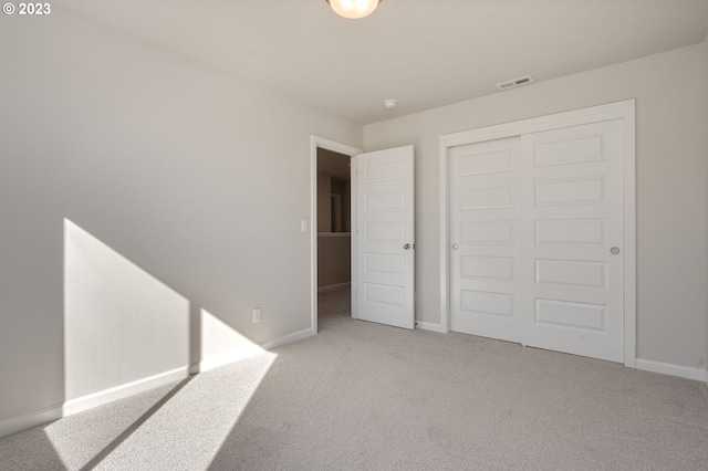 unfurnished bedroom with a closet and light colored carpet