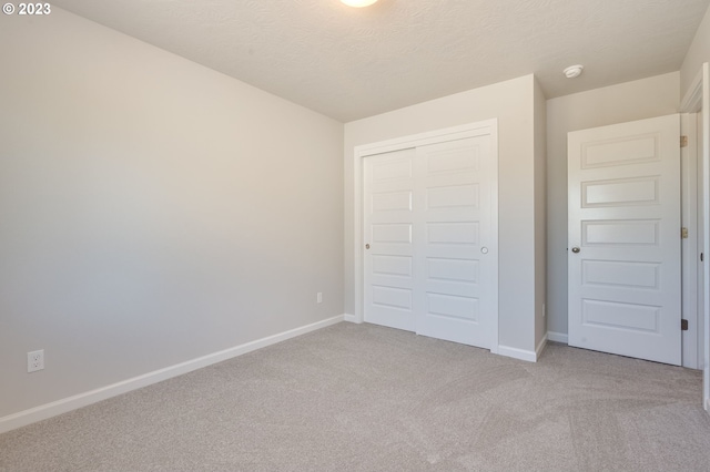 unfurnished bedroom with light carpet, a closet, and a textured ceiling