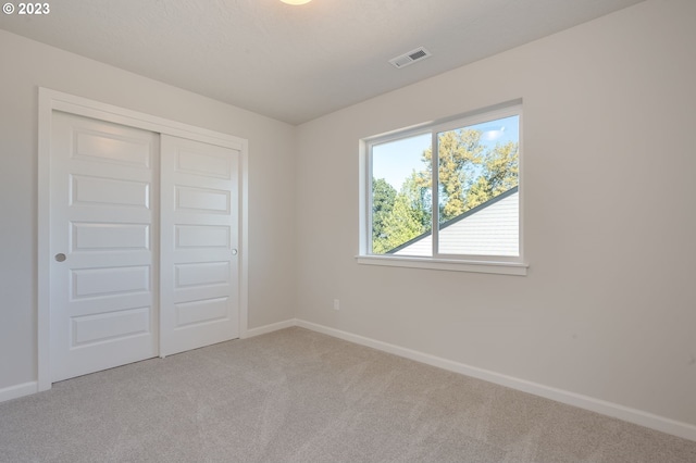 unfurnished bedroom with a closet and light colored carpet