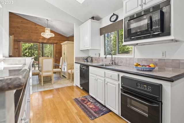 kitchen with wooden walls, an inviting chandelier, black appliances, and plenty of natural light