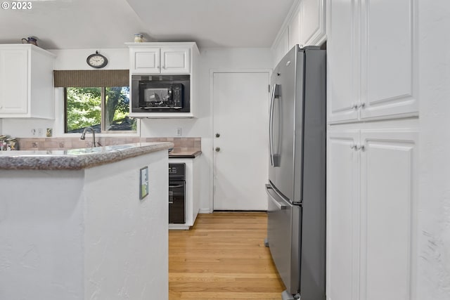 kitchen with light hardwood / wood-style floors, stainless steel refrigerator, white cabinets, and black microwave