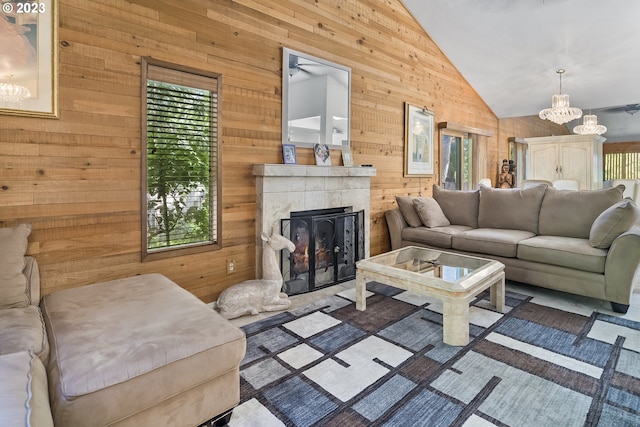 living room with high vaulted ceiling, ceiling fan with notable chandelier, and wooden walls