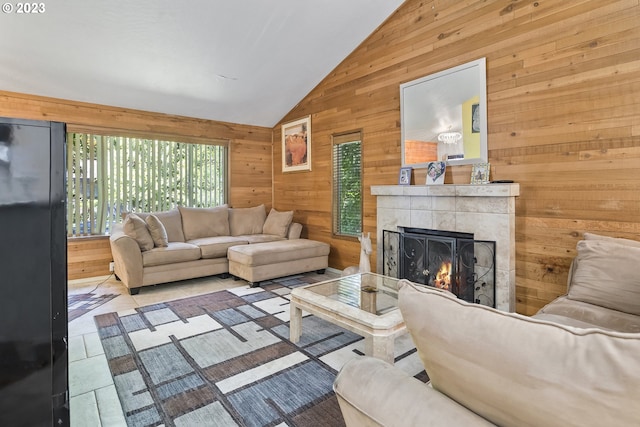 tiled living room featuring a tiled fireplace, wood walls, and lofted ceiling