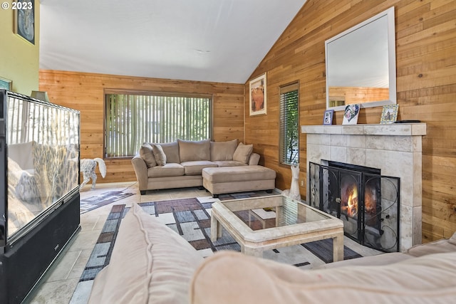 living room featuring lofted ceiling, a fireplace, wood walls, and light tile floors