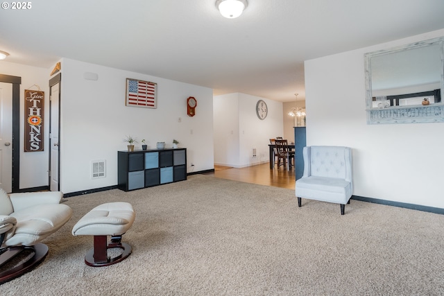 living area with a chandelier, carpet, visible vents, and baseboards