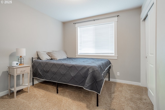 carpeted bedroom with a closet and baseboards