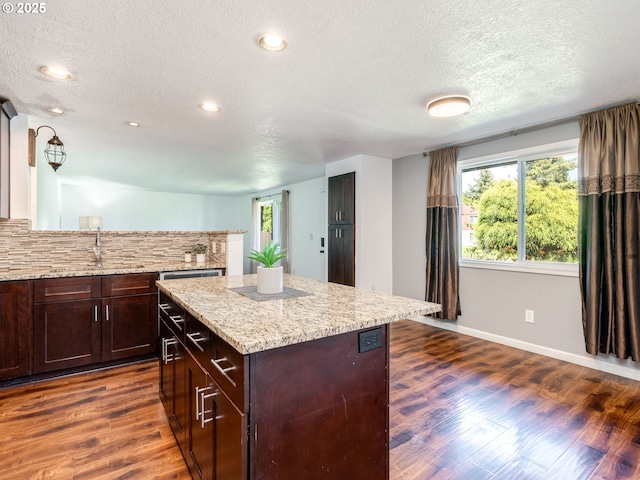 10204 NE 6th Ave, Vancouver, WA 98685 - kitchen with dark wood-style floors, a textured ceiling, backsplash, a kitchen island, and light stone counters