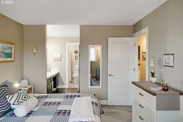 bedroom with dark carpet, ensuite bath, and a textured ceiling