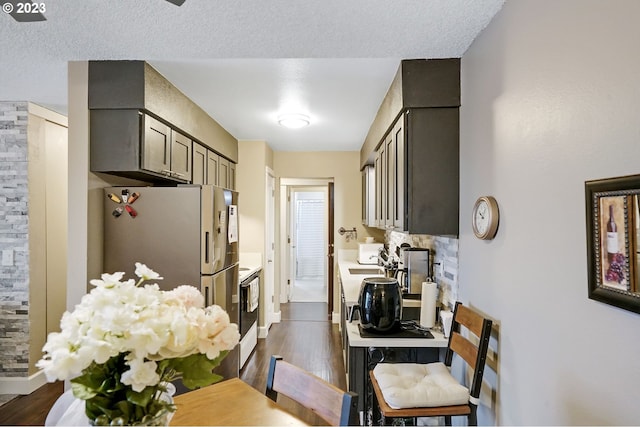 kitchen featuring stove, dark hardwood / wood-style floors, a textured ceiling, and white refrigerator