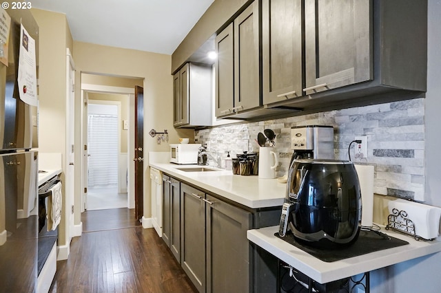 kitchen with stove, tasteful backsplash, stainless steel fridge, dark hardwood / wood-style floors, and sink