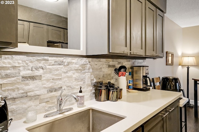 kitchen featuring a textured ceiling, sink, and tasteful backsplash