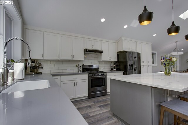 kitchen with stainless steel appliances, backsplash, decorative light fixtures, dark hardwood / wood-style flooring, and white cabinets