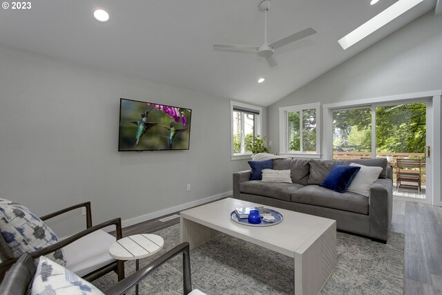 living room featuring a skylight, high vaulted ceiling, light hardwood / wood-style floors, and ceiling fan