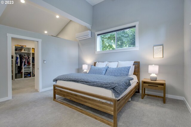 carpeted bedroom featuring high vaulted ceiling, a closet, a walk in closet, and a wall mounted air conditioner