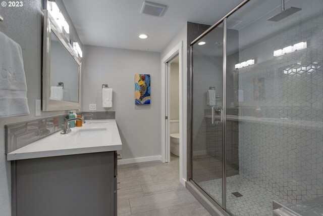 bathroom with walk in shower, tile floors, toilet, and double vanity