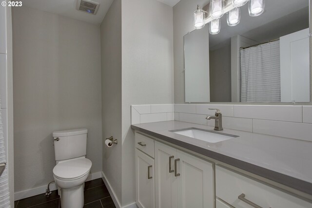 bathroom with vanity, toilet, tasteful backsplash, and tile floors