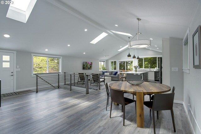 dining area with vaulted ceiling with skylight and light wood-type flooring