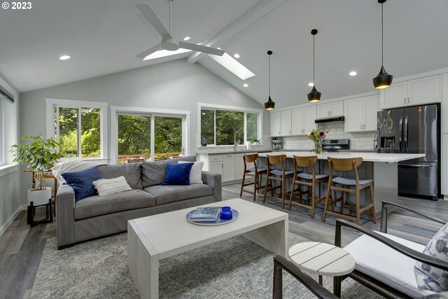 living room with a skylight, beam ceiling, plenty of natural light, and dark hardwood / wood-style flooring