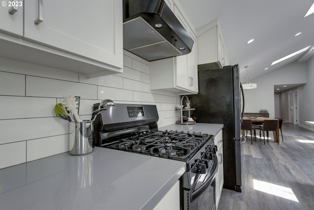 kitchen featuring light hardwood / wood-style floors, stainless steel range with gas stovetop, white cabinets, wall chimney exhaust hood, and lofted ceiling