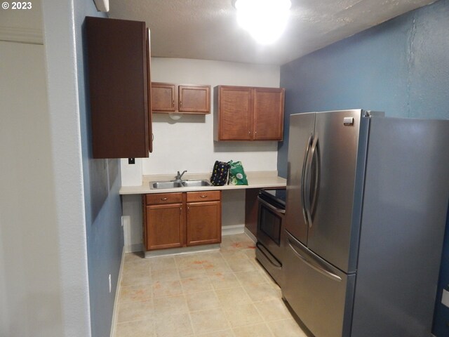 kitchen featuring light tile floors, sink, range with electric cooktop, and stainless steel refrigerator