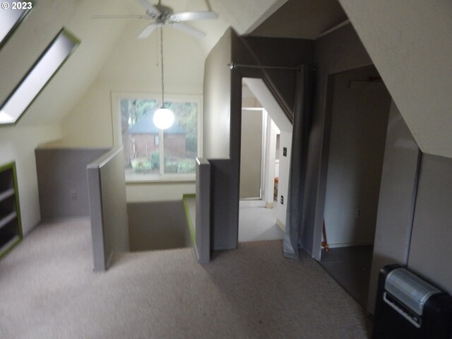 additional living space featuring ceiling fan, light colored carpet, and vaulted ceiling with skylight