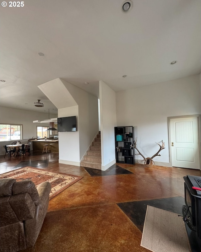 living area with stairway, concrete flooring, and baseboards