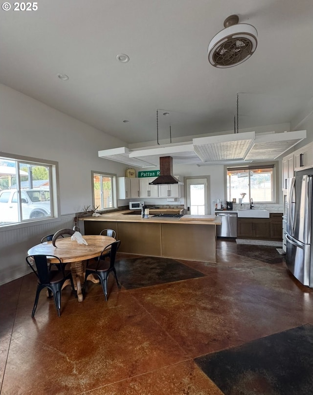 kitchen featuring a sink, stainless steel appliances, wainscoting, island range hood, and light countertops