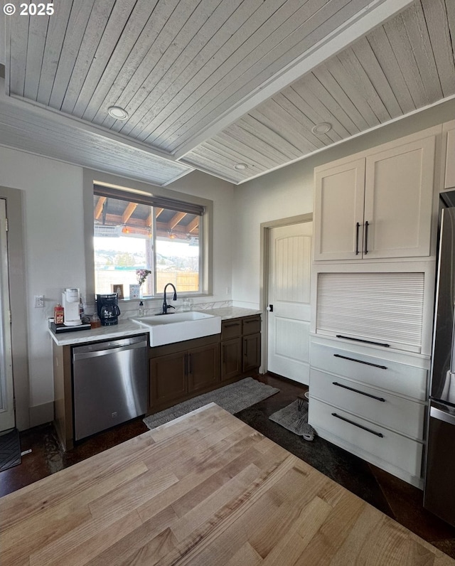 kitchen with a sink, wood finished floors, appliances with stainless steel finishes, light countertops, and wood ceiling