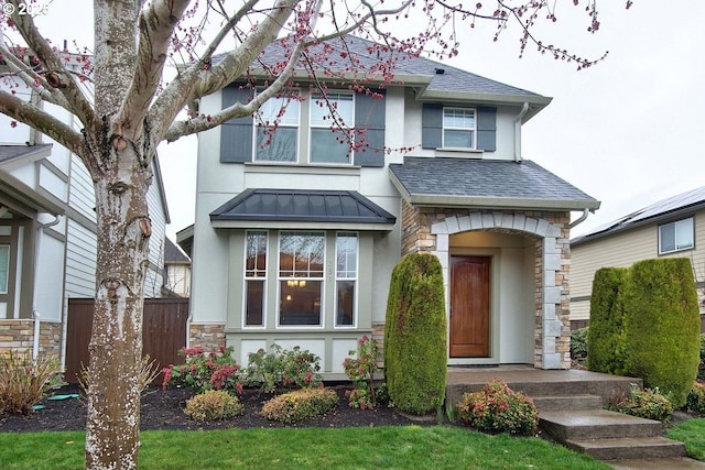 view of front of house with a standing seam roof, stone siding, fence, roof with shingles, and metal roof