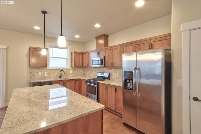 kitchen with tasteful backsplash, brown cabinets, appliances with stainless steel finishes, light wood-style floors, and a sink