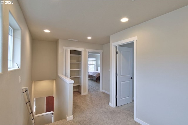 corridor with an upstairs landing, recessed lighting, light carpet, and baseboards