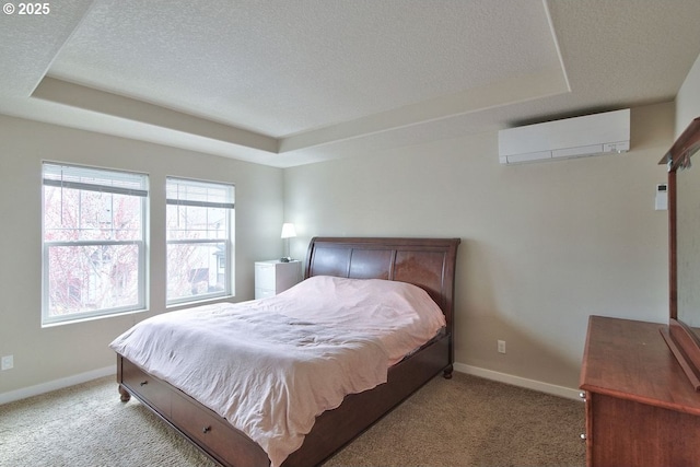 bedroom featuring an AC wall unit, baseboards, a tray ceiling, and light carpet