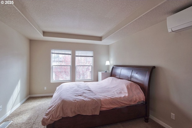 bedroom featuring visible vents, baseboards, carpet, a textured ceiling, and a wall mounted AC